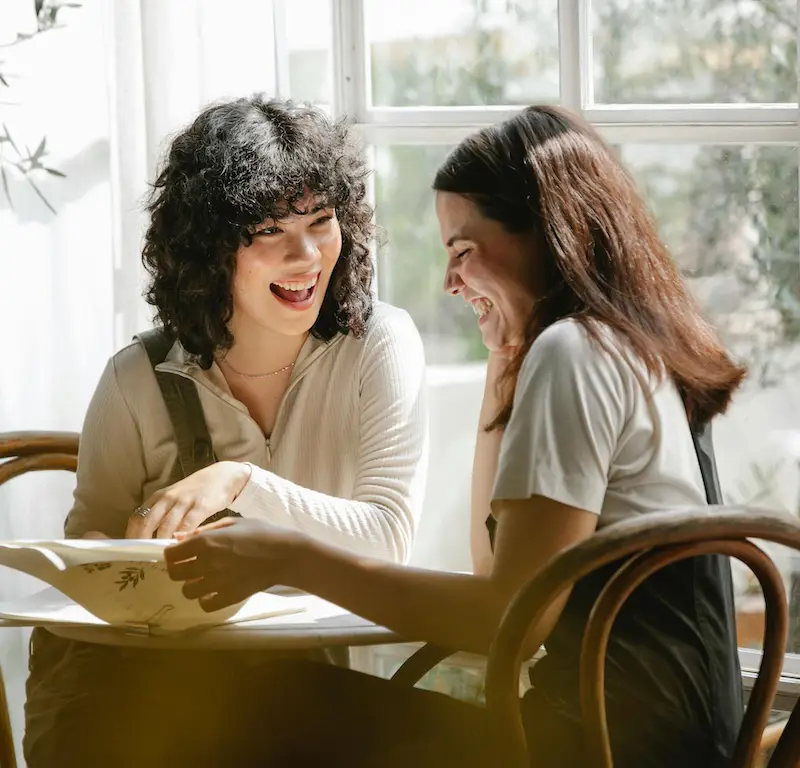 Two women laughing in a sunny room