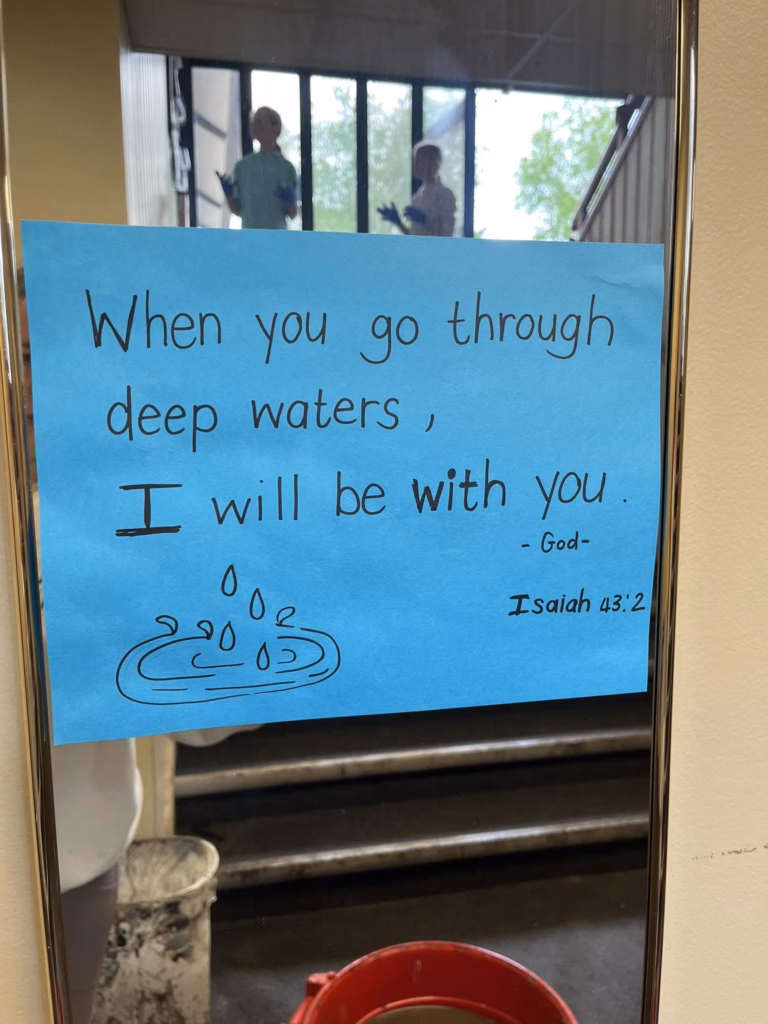 Poster on flooded church window with the bible verse "When you go through deep waters, I will be with you" Isaiah 43:2